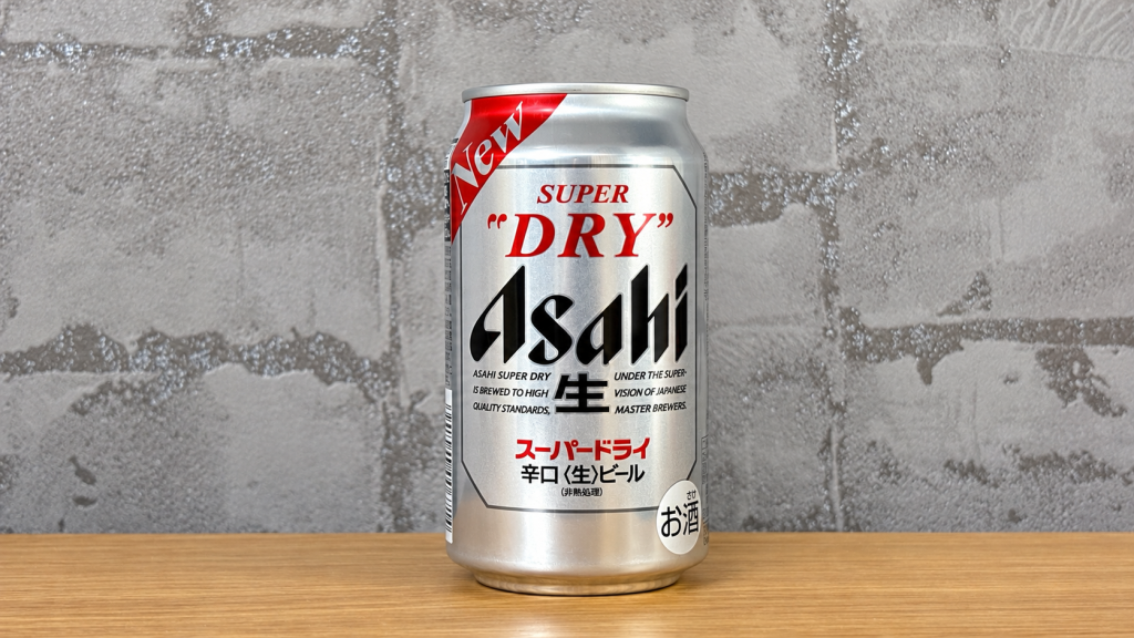 グレーの壁紙と木の天板を背景に中央に置いたアサヒスーパードライの缶