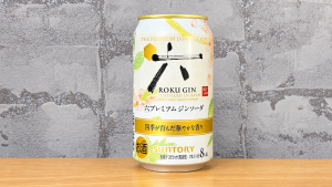 グレーの壁紙と木の天板を背景に置いた六プレミアムジンソーダ缶8％